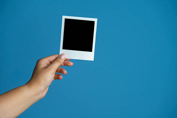 istock Hands Holding Blank Instant Photos on Blue Background 2230041267