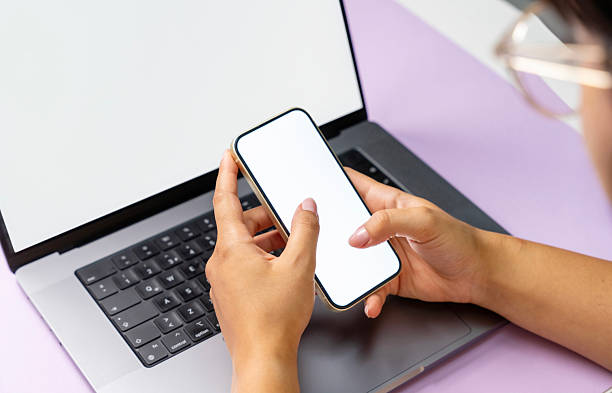 istock Hands Holding Smartphone in Front of Laptop on Modern Desk 2230052373