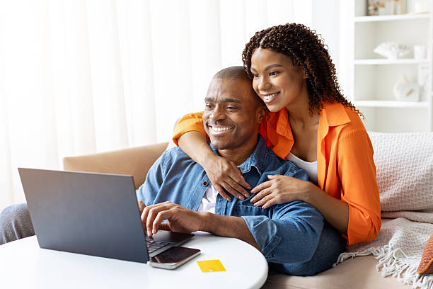 Smiling young African American couple using laptop at table at home