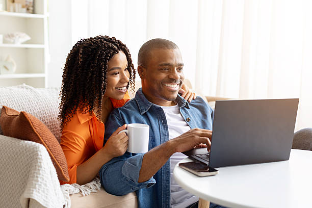 istock Smiling young African American couple using laptop at table at home, 2230056290
