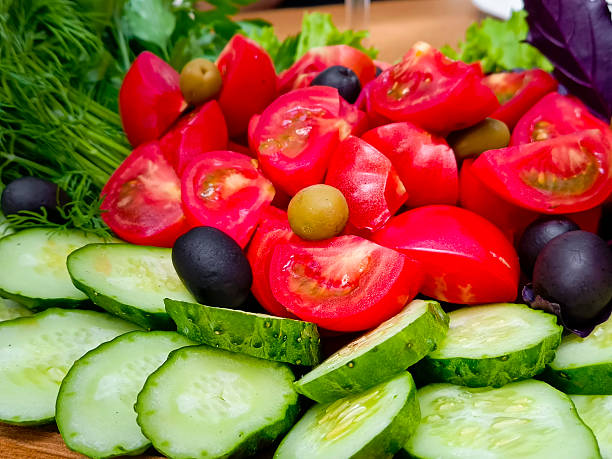 Sliced Fresh cucumbers, tomatoes and greens. Close-up, selective focus.