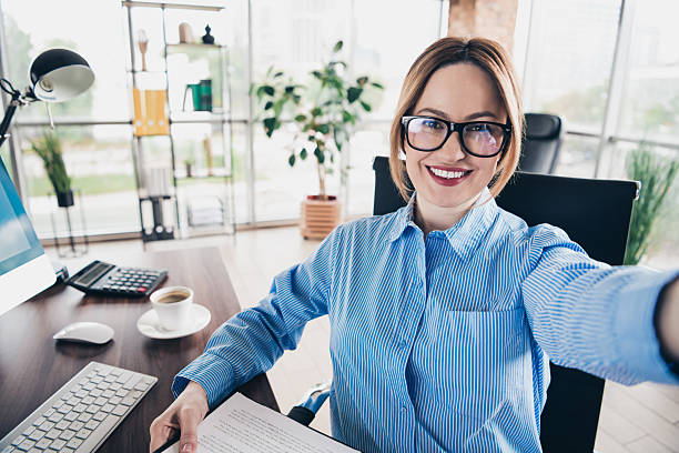 istock Smiling businesswoman in modern office taking selfie while enjoying a professional workspace with vibrant atmosphere 2230063161