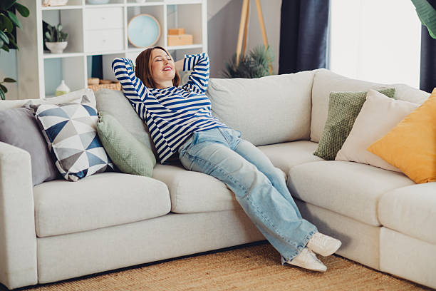 istock Young woman relaxing on a comfortable sofa at home while enjoying daylight during a cozy weekend indoors 2230063636