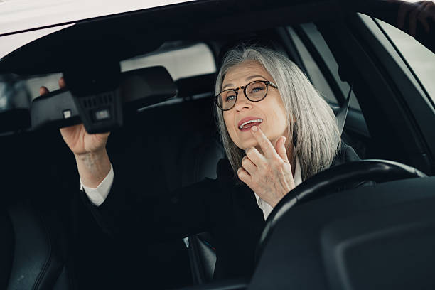 istock Successful mature woman adjusting rearview mirror while sitting in a car showcasing elegance and professionalism 2230063702