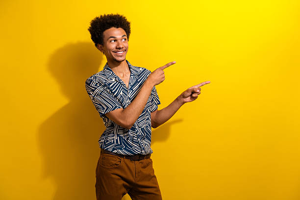 istock Casually dressed young man gesturing with both hands against a vibrant yellow background representing happiness and positivity 2230064408