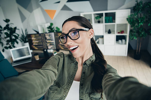 istock Young woman programmer takes joyful selfie in modern workspace with computer screens and coding on display 2230064616