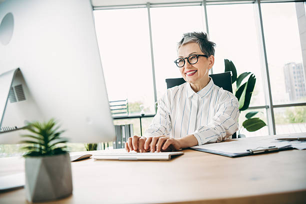 istock Confident mature businesswoman working in modern office using desktop computer with a professional and engaging demeanor 2230065345