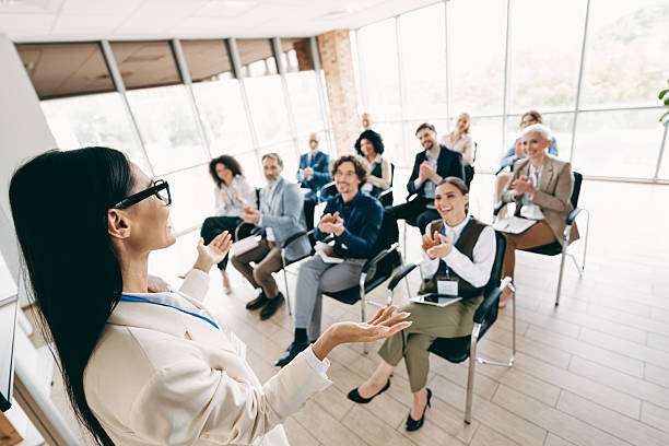 istock Team leader conducting an engaging professional presentation in a bright office space with applauding attendees 2230065443