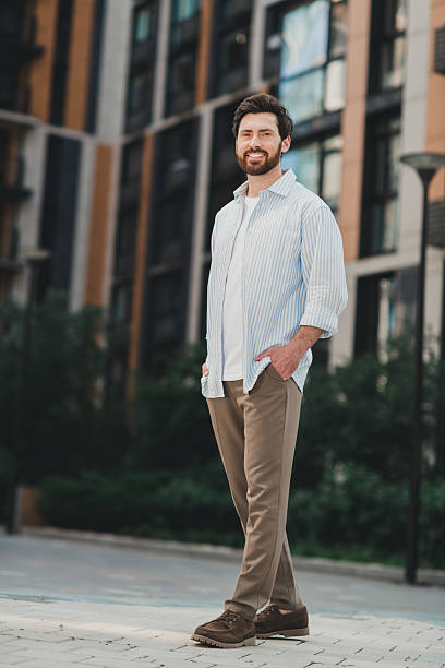 istock Confident young man exploring urban streets with a friendly smile surrounded by modern architecture on a sunny day 2230066157