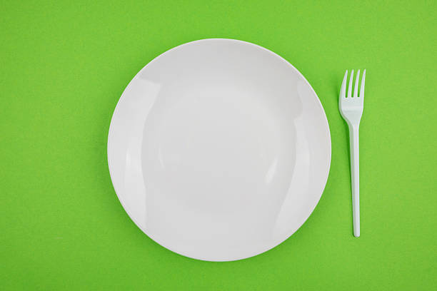 istock white plate and white fork on a green background. 2230067144