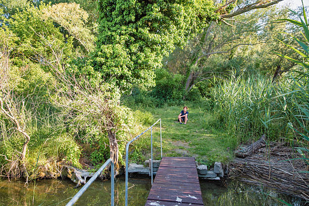 istock Wooden pier leading to green forest path 2230068985