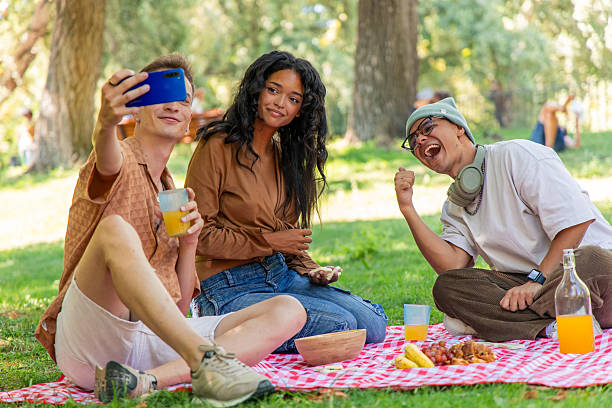 istock Multicultural friends taking selfie while having picnic in park 2230070637