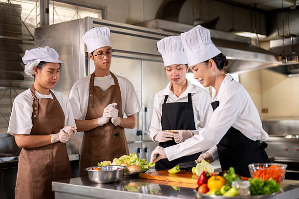 istock Female chef picking bell peppers while her students or assistants standing around the kitchen counter. 2230071150