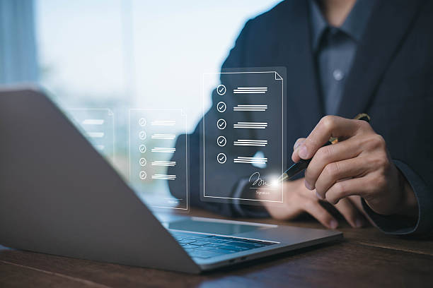 istock Digital document checklist concept with businessman using laptop to review tasks, approve items, and sign forms, representing paperless workflow and online business management. signature e document 2230071517