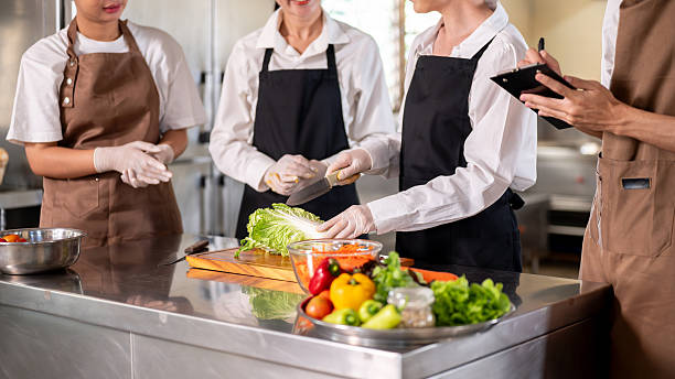 istock Female chef teaching and explaining how to cut cabbage to students or assistants at kitchen counter. 2230071733