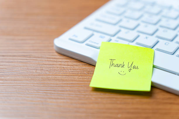 A sticky note with Thank You on the corner of a computer keyboard. Gratitude, appreciation, recognition, and positive interaction in a modern workspace.