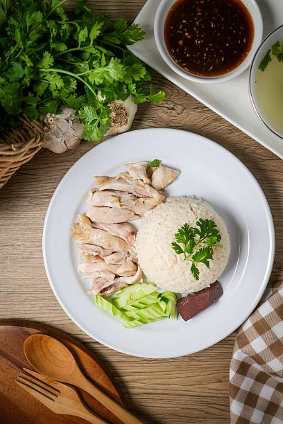 Chicken and rice with coriander and cucumber with sauce and soup in a white plate, hainanese chicken rice, thai called khao man gai, asian food, thai food