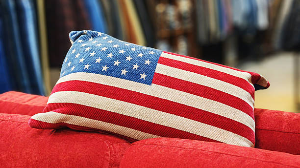 A decorative pillow displaying the American flag rests on a bright red couch inside a retail store.