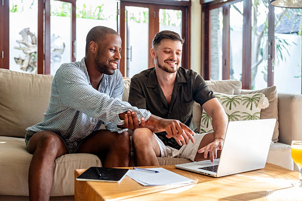 istock Two Men Enjoying Leisure Time Together Using a Laptop in a Comfortable Living Room 2230083504