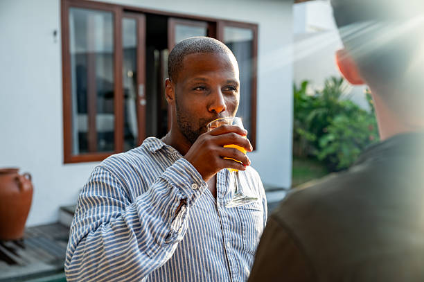 istock Man Drinking Beverage Outdoors Engaging in a Friendly Conversation with Another Person 2230083538