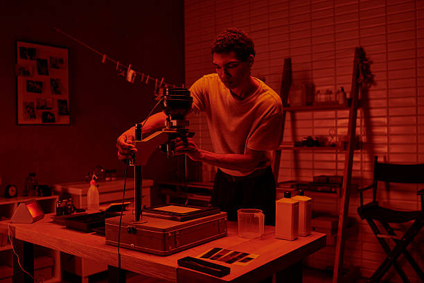 istock Young man explores film developing in a cozy darkroom with artistic flair 2230086169