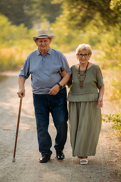 A little girl accompanies her grandfather, needing constant care, on a walk in the public park, Turin, showing much patience and love. The man walks with difficulty with a cane.