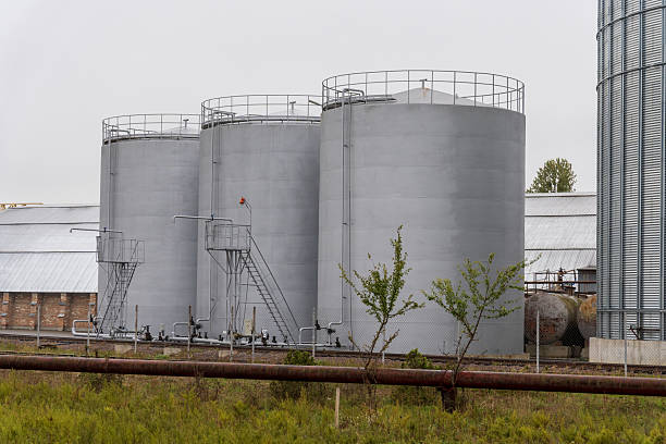 istock Tall grey silos/tanks in grassy field. Railway tracks, pipeline in front. Overcast 2230088666