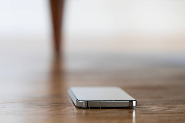Lost mobile phone dropped on a wooden floor under a sofa