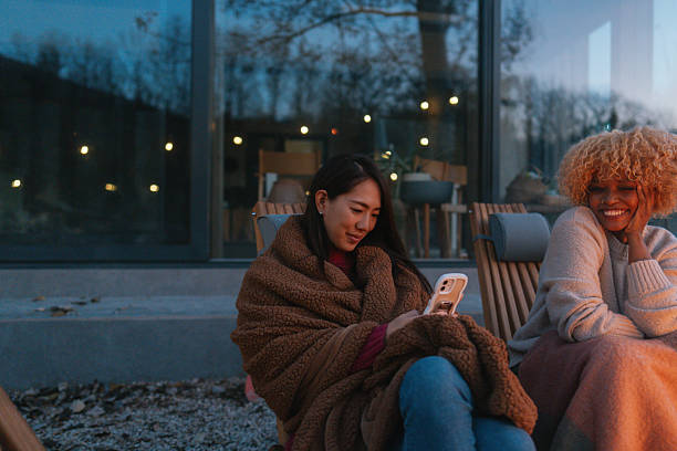 Photo of a couple of female friends,  relaxing by the campfire at dusk