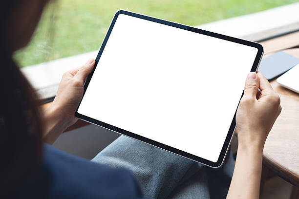 istock Mockup balnk screen digital tablet. Woman holding digital tablet with blank white screen with laptop computer on table at coffee shop, template for web app design or social media marketing 2230097070