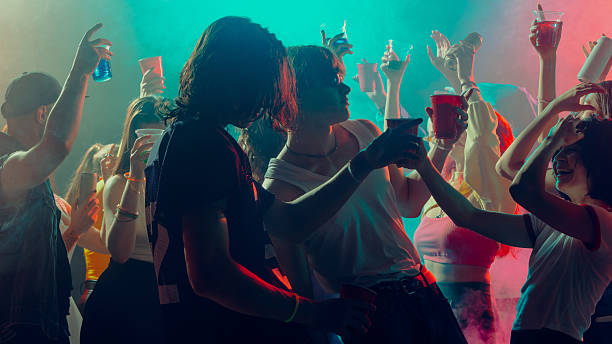 istock People celebrating at a vibrant party with drinks in hand, colorful lights create a lively atmosphere. 2230098549