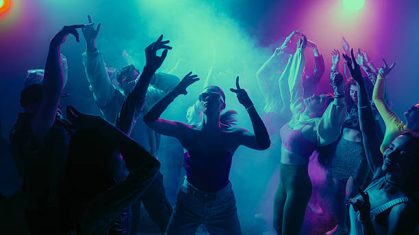 istock A vibrant party scene with diverse people dancing under colorful lights. 2230098554