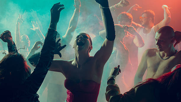 Shadows of dancing people show up in red light on a dance floor.