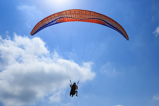 Two para gliders glide gracefully through clear skies amidst picturesque clouds and rolling hilltops, Embracing freedom and the beauty of nature.
