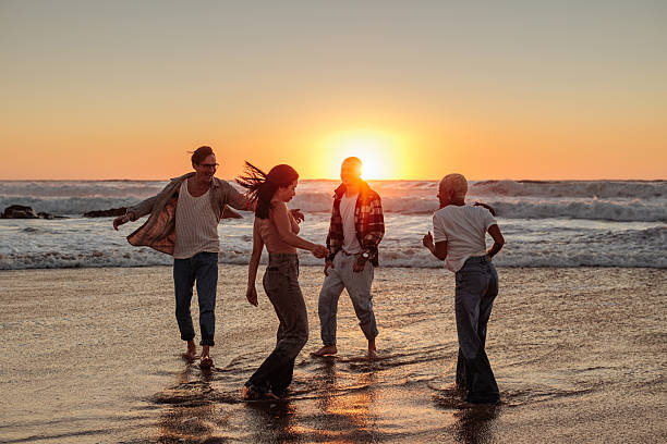 istock Friends dancing together on the beach at sunset 2230103161
