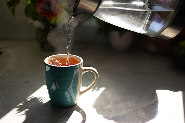 Hot Water Being Poured Into a Tea Cup With Steam Rising in a Cozy Kitchen Setting