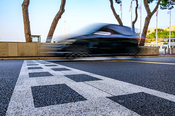 Monaco Grand Prix finish line with a car passing  by over the checkerd flag strip on the tarmac. Photo with motion blur.