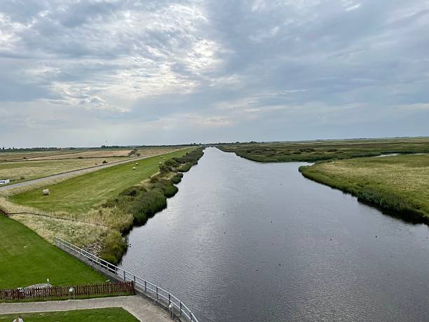 istock Serene river landscape with cloudy skies and fields. 2230115051