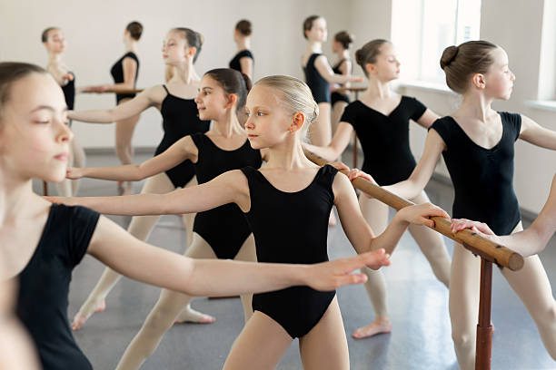 istock Young ballerinas rehearsing in the ballet class. They perform different choreographic exercises. They stand in different positions near the ballet barr. 2230117118