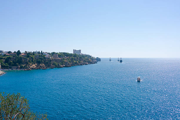 The ocean is a beautiful shade of blue, with a boat floating in the middle of it. The boat is small and he is a fishing boat. The water is calm and peaceful, with no signs of any waves or currents