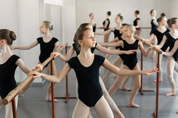 istock Young ballerinas rehearsing in the ballet class. They perform different choreographic exercises. They stand in different positions near the ballet barr. 2230119006