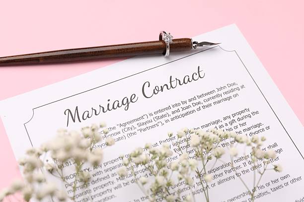 istock Marriage contract, flowers, pen and ring on pink background, above view 2230120161