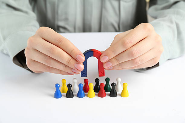 istock Woman with magnet attracting game pieces at white table, closeup 2230120723