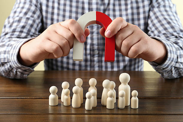 istock Man with magnet attracting game pieces at wooden table, closeup 2230120746