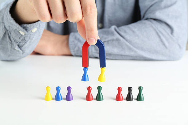 istock Man with magnet attracting game pieces at white table, closeup 2230120748