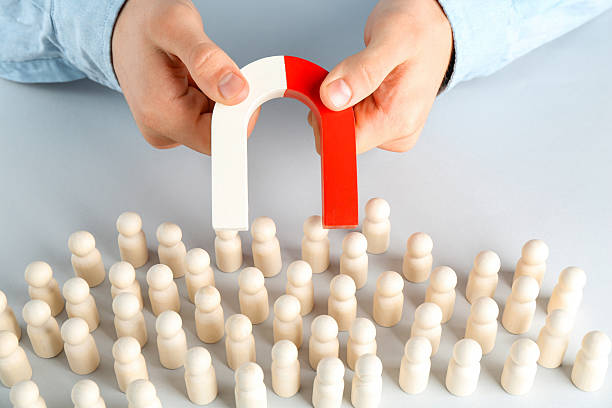 istock Man with magnet attracting game pieces at white table, closeup 2230120754