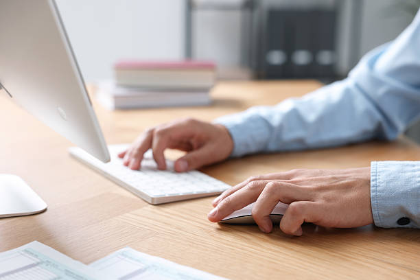 istock Man working on computer at wooden desk in office, closeup 2230121259