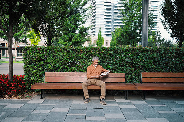 istock Senior man sitting on the bench reading magazine 2230121666
