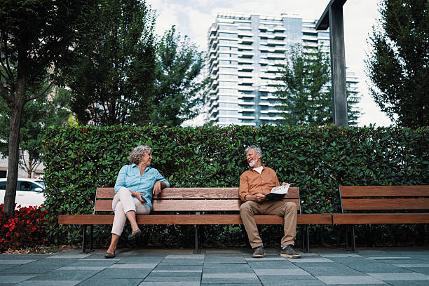 istock Strangers sitting together on a park bench 2230121679