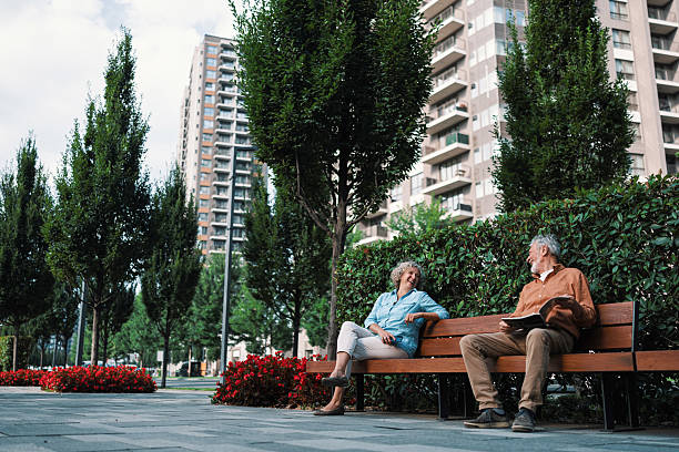 istock Strangers sitting together on a park bench 2230121694